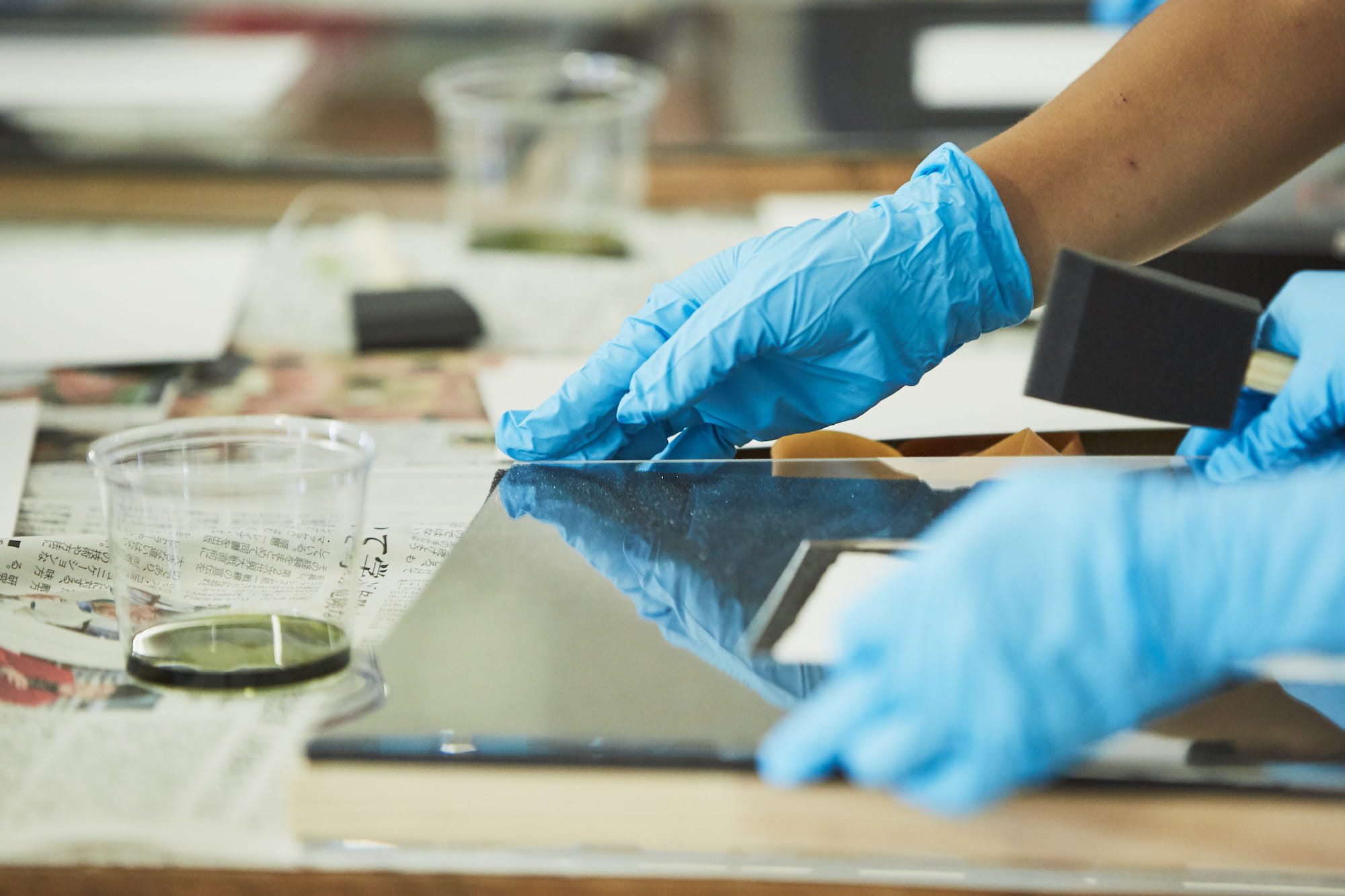 スポンジに感光液（シュウ酸鉄アンモニウム）と現像液（フェリシアン化カリウム）を混合した薬品を含ませ、紙全体に塗っていきます