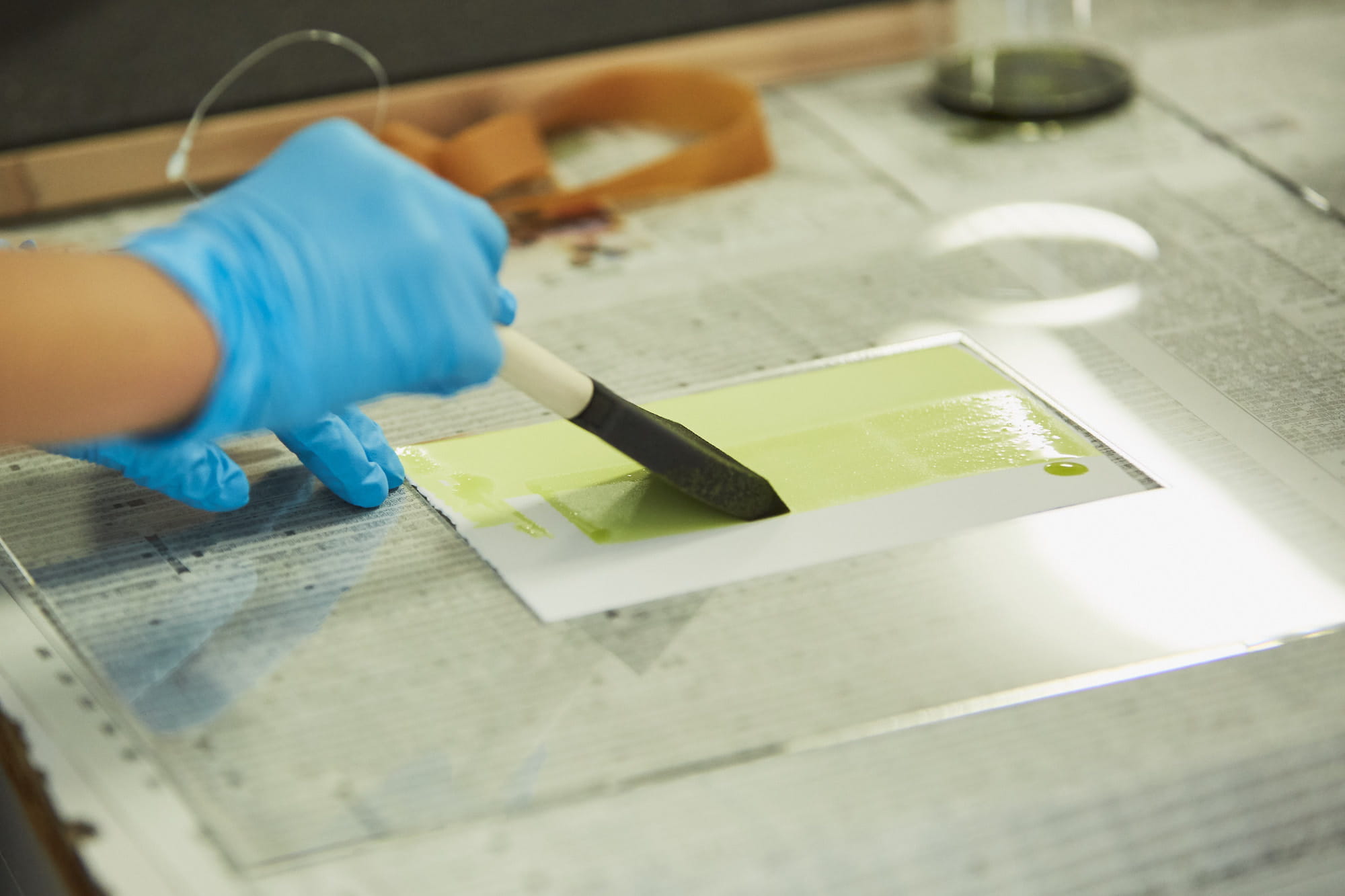 スポンジに感光液（シュウ酸鉄アンモニウム）と現像液（フェリシアン化カリウム）を混合した薬品を含ませ、紙全体に塗っていきます