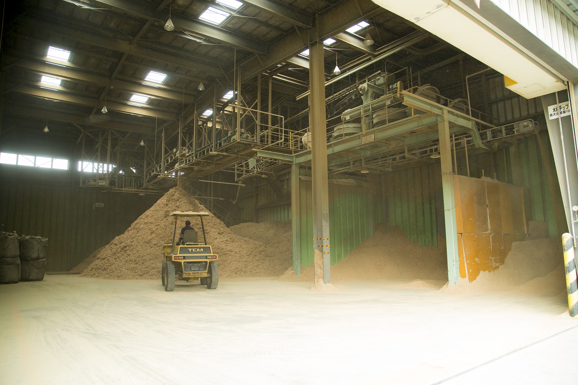 リサイクル炭化プラントに持ち込まれた廃材の山（上段）と、用途別に3段階に粉砕されたチップ（下段）。このうち7割が炭八の材料として炭化炉に回される