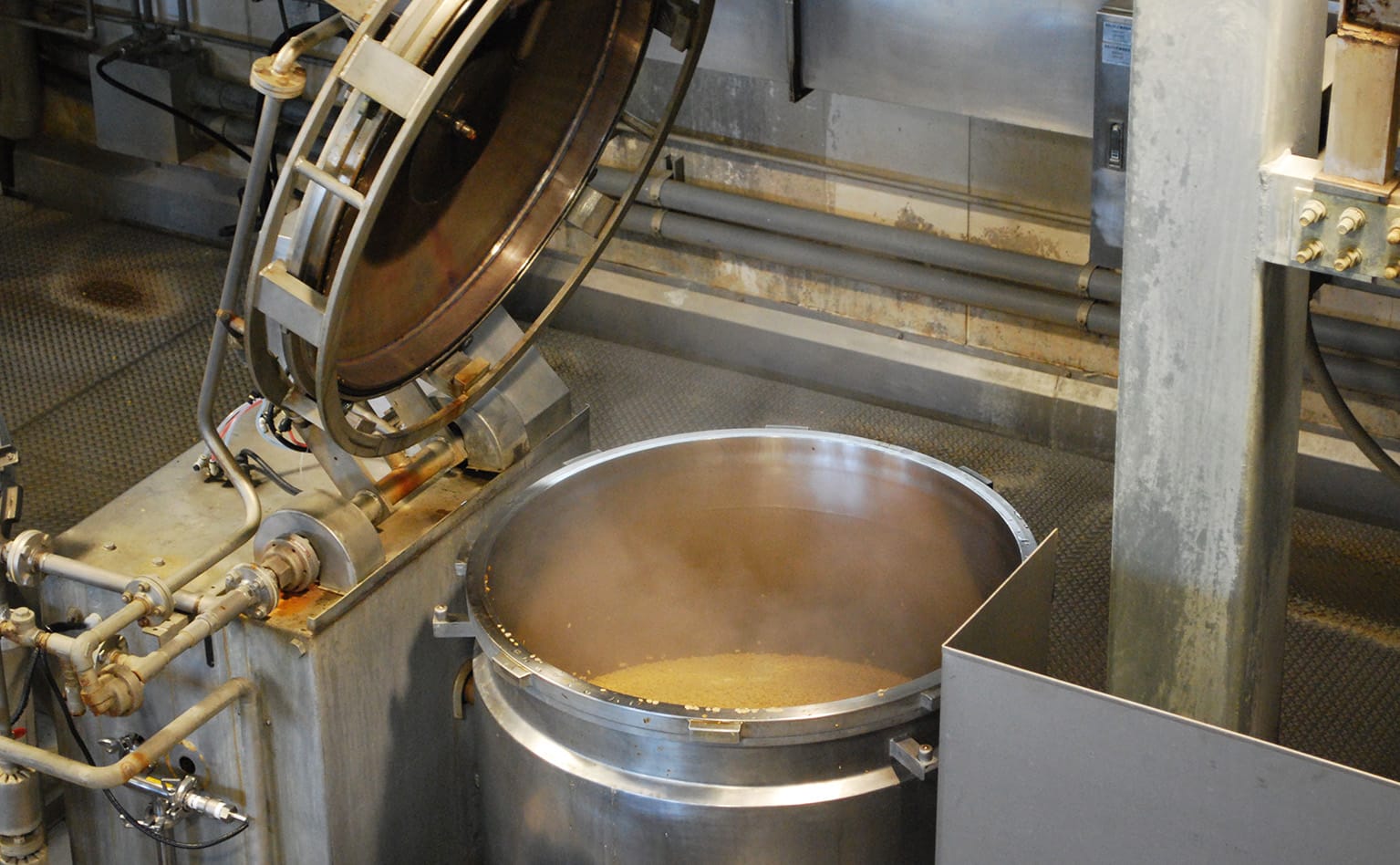 納豆の製造工程では、大きな釜で蒸した大豆に、納豆菌をムラなくスプレーする （画像提供：タカノフーズ株式会社）